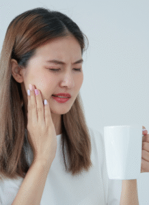 a lady feeling pain in her tooth when drinking hot tea